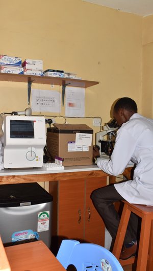 Lab technician working at a microscope in a small clinic laboratory