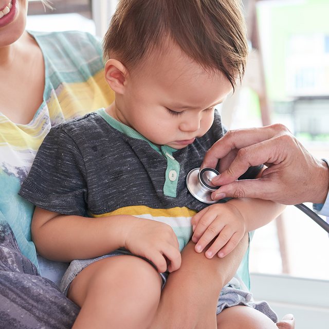 Little boy watching as a doctor listens to his chest with a stethoscope