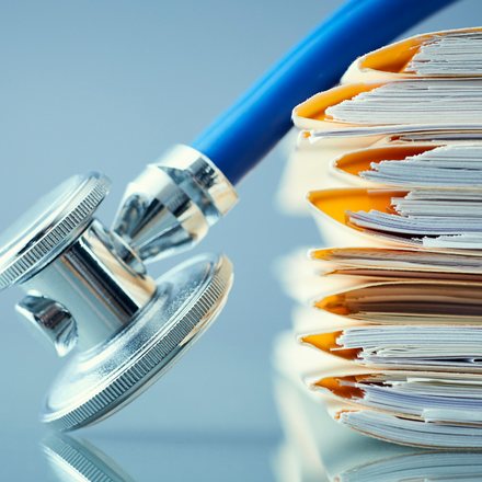 Stethoscope resting on a stack of patient files
