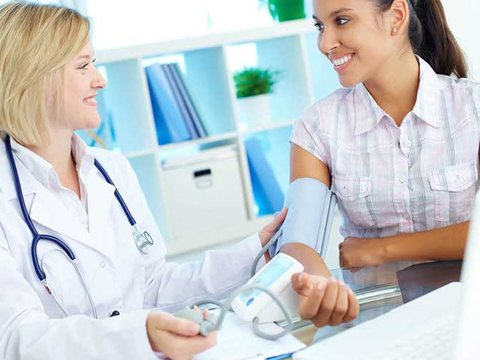 Doctor checking a woman's blood pressure