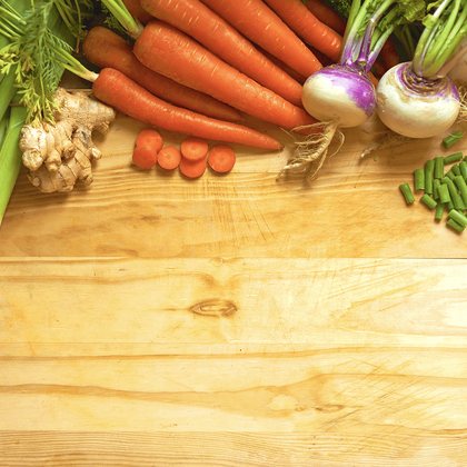 Fresh carrots, beetroot, turnips and greens around a wooden board