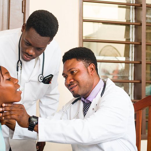 Two doctors gently checking a young girl's throat